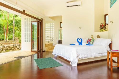 a bedroom with a bed and a bathroom at Colores del Viento - by Pura Villas in Uvita