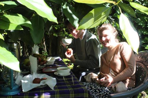 Nyarugina的住宿－Under Volcanoes View Guest House，坐在餐桌旁吃食物的男人和女人