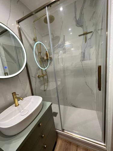 La salle de bains est pourvue d'une douche et d'un lavabo blanc. dans l'établissement Appartement cosy avec jardin proche de la gare, à Boulogne-sur-Mer