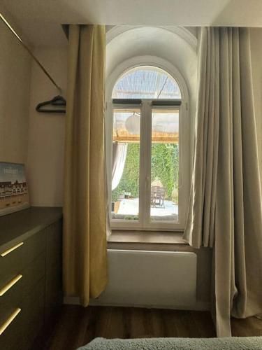 une chambre avec une fenêtre cintrée avec des rideaux dans l'établissement Appartement cosy avec jardin proche de la gare, à Boulogne-sur-Mer