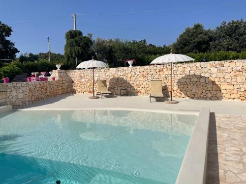 een zwembad met 2 stoelen en een stenen muur bij Villa Dei Fiori in Locorotondo