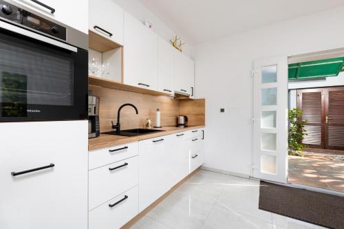克爾克的住宿－Apartment Kamila，一间厨房,配有白色的橱柜和大窗户