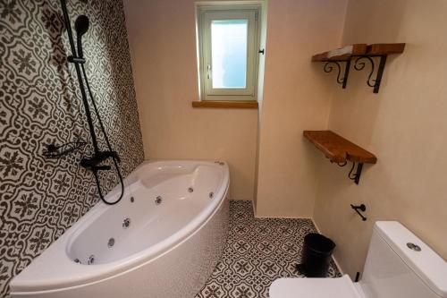 a white bath tub in a bathroom with a window at Nostos Country House in Tsagarada