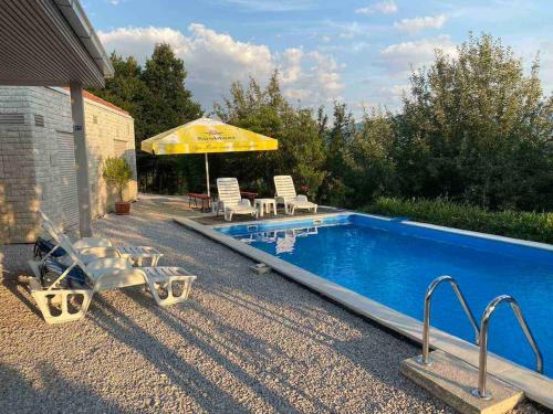 a swimming pool with chairs and an umbrella at Woodrock Villa in Sarajevo