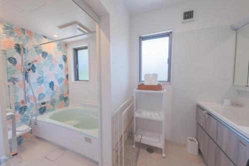 a white bathroom with a tub and a sink at Through Time Amami - Vacation STAY 58444v in Amami