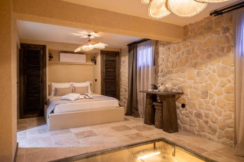 a bedroom with a bed and a stone wall at BİADA OTELLERİ in Bozcaada