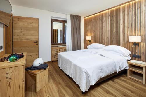 a bedroom with a large white bed and a television at Hotel Garni dello Sportivo in Madonna di Campiglio