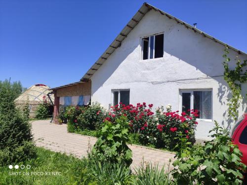 a white house with red flowers in front of it at Guest House Doktor Eismann in Chychkan