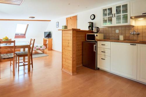 a kitchen with white cabinets and a table with a microwave at Chata Harmonie in Bedřichov