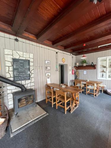 a dining room with tables and a wood stove at Horská Chata Gírová in Bukovec