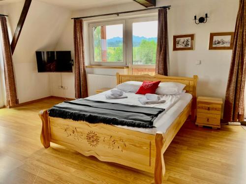 um quarto com uma cama de madeira e uma grande janela em Willa Widokowa em Bukowina Tatrzańska