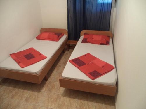 two beds in a room with red pillows on them at Vito Apartments Sutomore in Sutomore