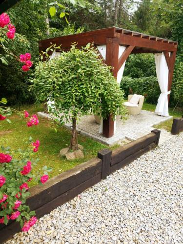 a pavilion with a bench and a tree in a garden at Karczma Karnasów in Cisna