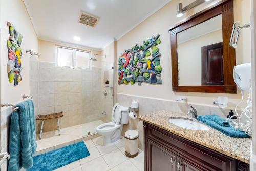 a bathroom with a sink and a toilet and a mirror at The Palms 603 in Jacó