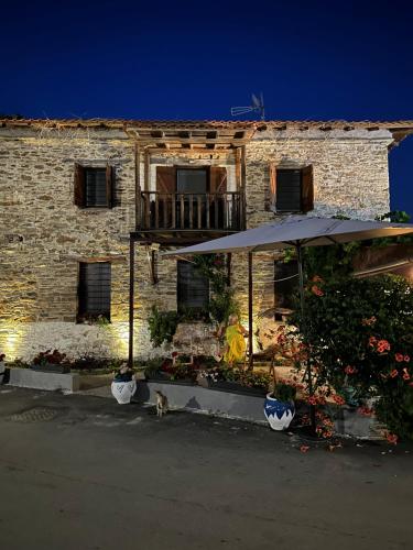 a cat sitting in front of a building with an umbrella at Petrospito by the sea! in Neos Marmaras