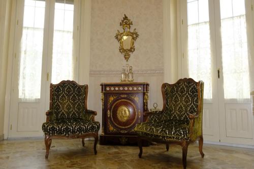 2 sillas y un reloj en una habitación con ventanas en Palazzo Vitrano - tourist apartment, en Catania