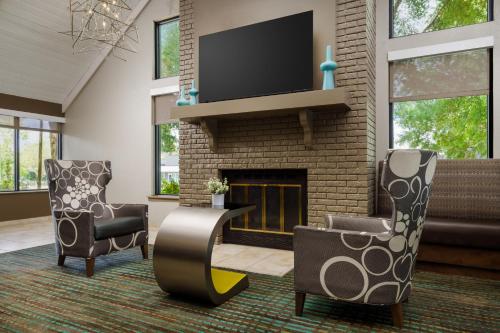 sala de estar con 2 sillas y chimenea en Residence Inn Orlando Altamonte Springs / Maitland en Orlando