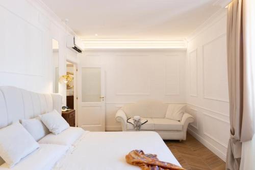 a white bedroom with a white bed and a couch at Île Déluxe Apartment in Sorrento