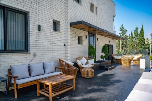 eine Terrasse mit einem Sofa und Stühlen sowie ein Gebäude in der Unterkunft Rokah Luxury Hotel at Ramat HaHayal in Tel Aviv