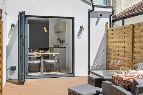 a patio with a table and chairs and a door leading to a kitchen at Cosy & Bright Home with Backyard in Southsea Portsmouth in Portsmouth
