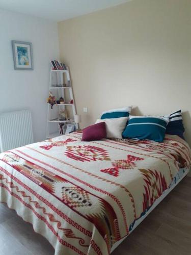 Schlafzimmer mit einem Bett mit einer roten und weißen Decke in der Unterkunft Appartement à 15 min de l'océan in Bayonne