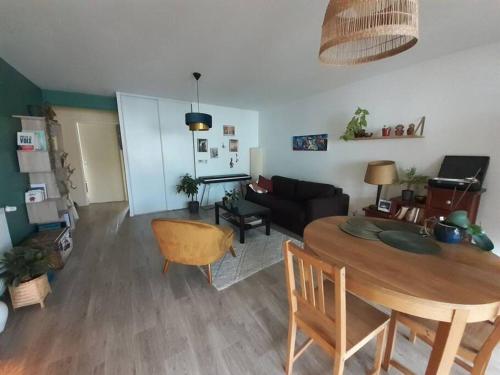 ein Wohnzimmer mit einem Tisch und einem Sofa in der Unterkunft Appartement à 15 min de l'océan in Bayonne