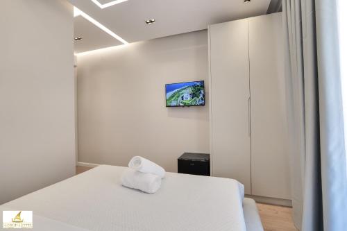 Una habitación con una cama blanca con una toalla. en NORGE HOTEL, en Ksamil