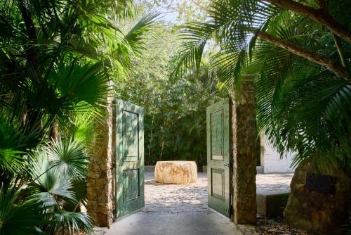 an open door in a garden with palm trees at Chablé Yucatan in Chocholá