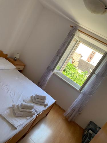 a bedroom with a bed and a window with towels at Apartman Lucic C in Dubrovnik