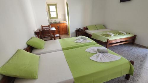 two beds in a room with green sheets at Palm Studios in Perissa