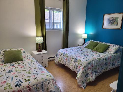 two beds in a bedroom with blue walls at Auberge Soleil de Mer in Bonaventure