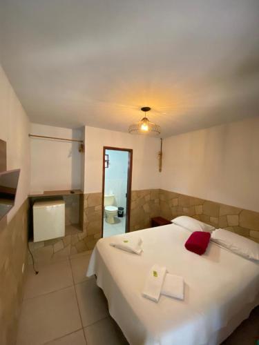 a bedroom with a large white bed with red pillows at Pousada Thamalu in Paraty
