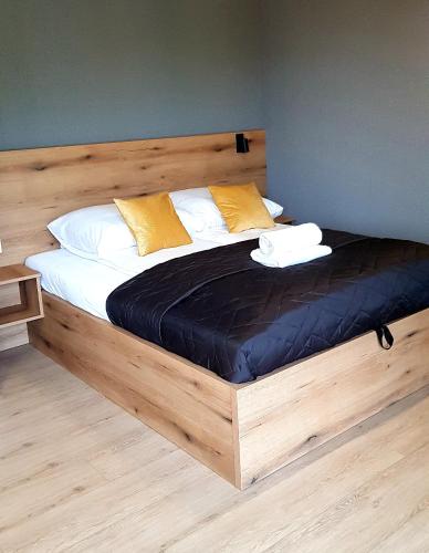a large bed with a wooden frame in a room at Apartamenty Cicha - bezpłatny parking in Krynica Zdrój
