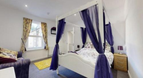 a bedroom with a canopy bed with purple curtains at Myrtle villa 10 bedrooms sleeps 28, 2 min to beach in Weymouth