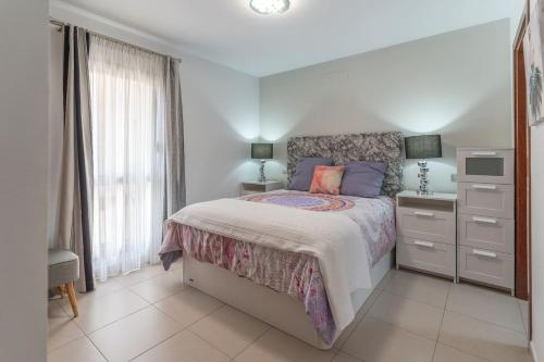 a white bedroom with a bed and a dresser and window at CASA ANA in Alcalá