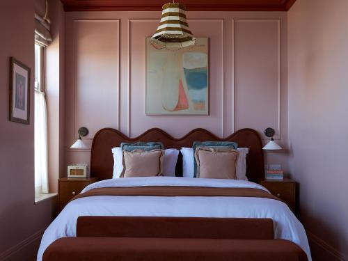 um quarto com uma cama grande com lençóis brancos e almofadas em Margate House em Kent