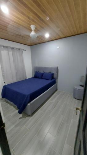 Schlafzimmer mit einem Bett mit blauer Bettwäsche und einer Holzdecke in der Unterkunft Casas Dñ Juanita in Jacó