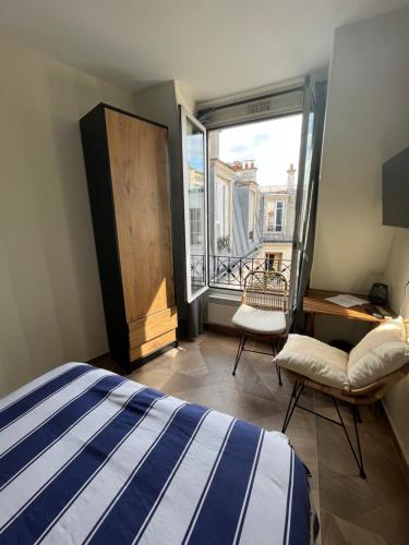 une chambre avec un lit et une grande fenêtre dans l'établissement Studio quartier Batignolles, à Paris