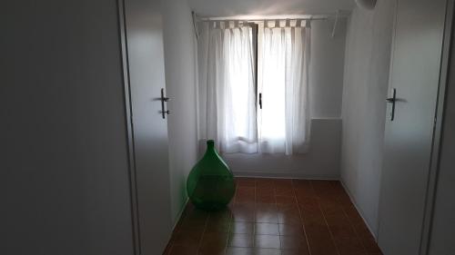 a green vase sitting on the floor in a room with a window at Dimora Chiara in SantʼAngelo