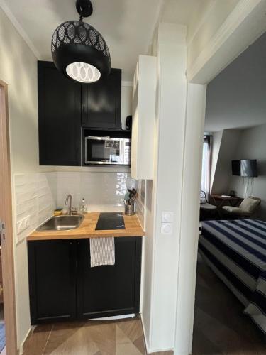 une petite cuisine avec un évier et un micro-ondes dans l'établissement Studio quartier Batignolles, à Paris