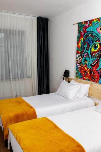 two beds in a hotel room with a painting on the wall at Hydeout Bakuriani in Bakuriani