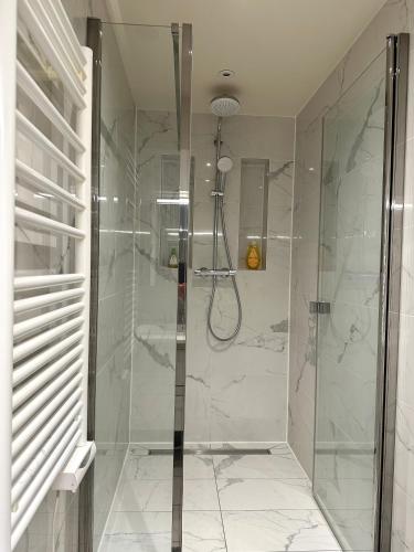 une salle de bain avec une douche avec une porte vitrée dans l'établissement Cosy, appartement refait à neuf limite 16, à Boulogne-Billancourt