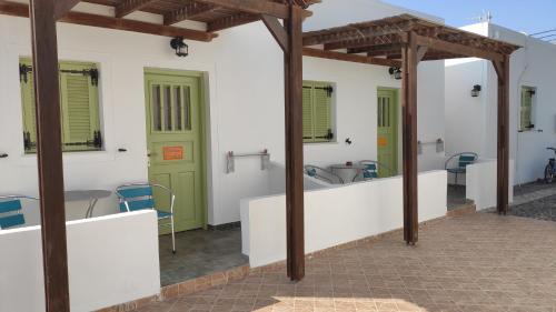 a patio with green doors and a table and chairs at Palm Studios in Perissa