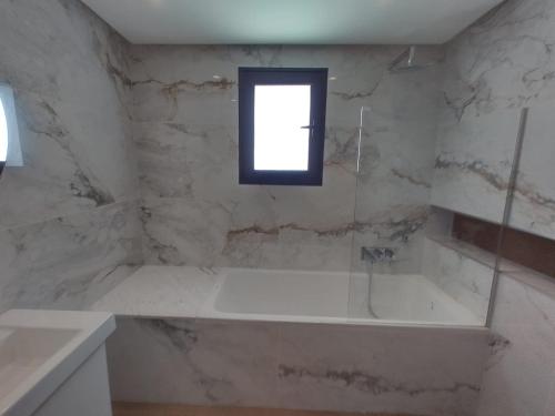 a bathroom with a bath tub and a window at Villa Nesrine in Hammamet Sud