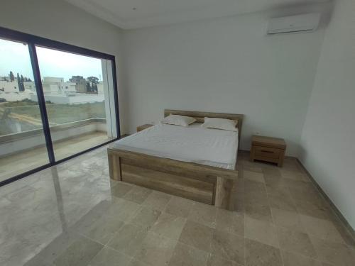 a bedroom with a bed and a large window at Villa Nesrine in Hammamet Sud