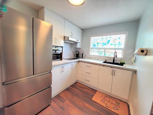 a kitchen with white cabinets and a stainless steel refrigerator at Cozy and quiet house with swimming pool in Toronto