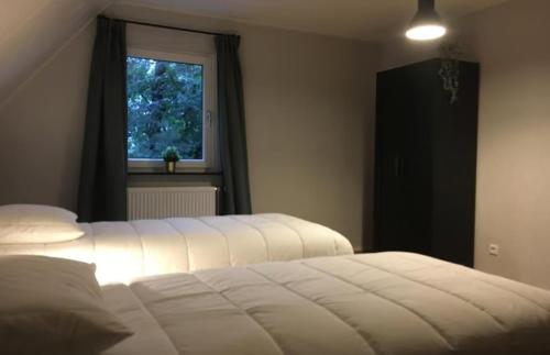 2 witte bedden in een slaapkamer met een raam bij Luxe boshuis in hartje Drenthe in Spier