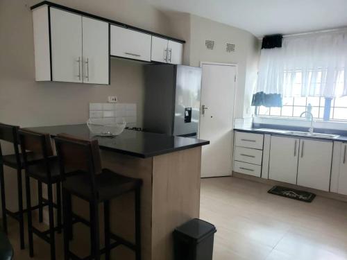 a kitchen with a counter and chairs in a room at A Home Away From Home in Lusaka