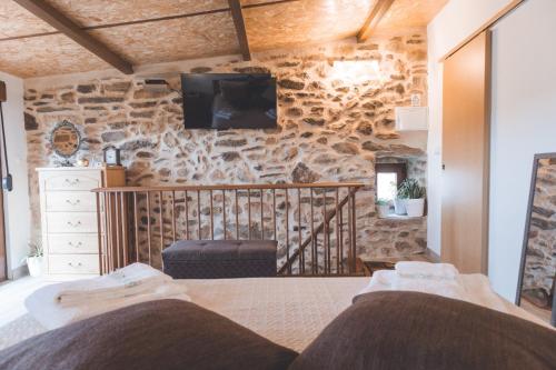um quarto com uma parede de pedra, uma cama e uma televisão em Casa da Vovó Luisa 
