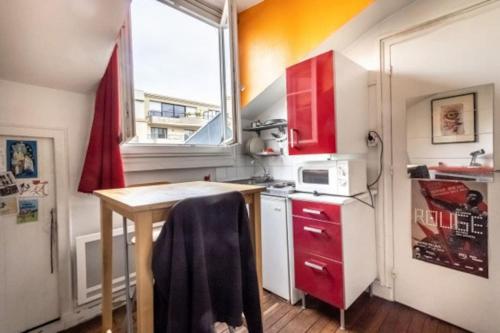 uma pequena cozinha com armários vermelhos e uma mesa em Penthouse by Roland-Garros em Boulogne-Billancourt